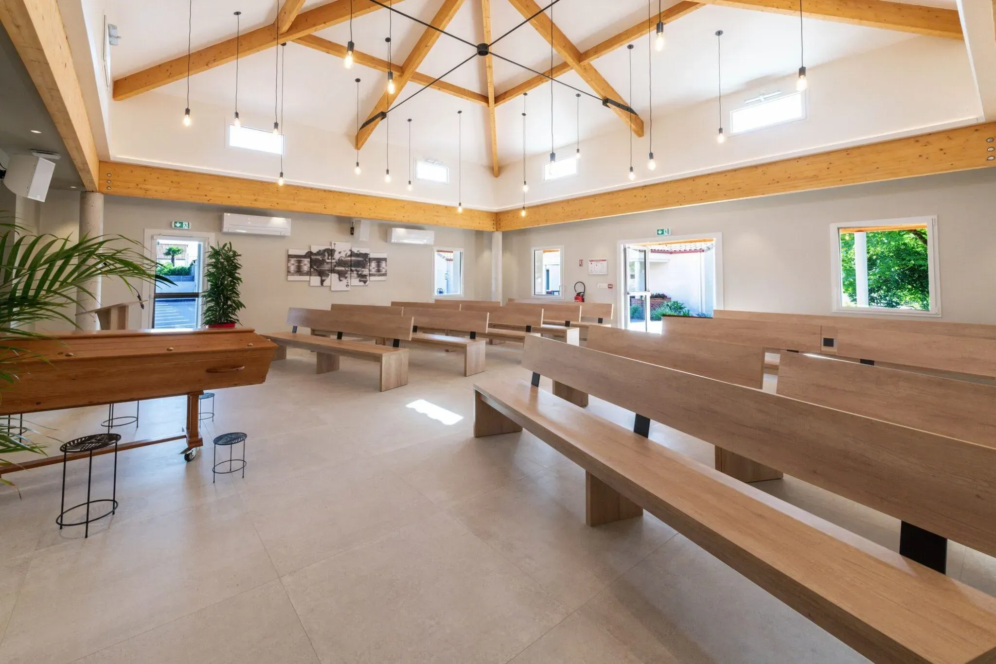 Salle de cérémonie funéraire spacieuse avec bancs en bois et cercueil.