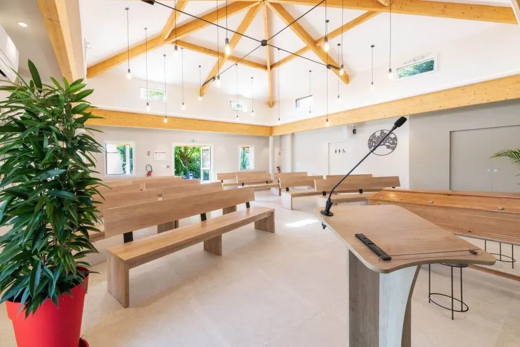 Salle de cérémonie lumineuse avec charpente apparente en bois et pupitre.